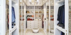 A luxury modern walk-in closet with clothes, accessories and mirror cabinets.