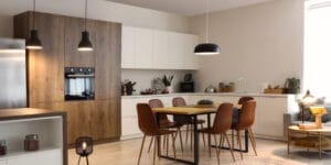 A modular open kitchen with dining table and glowing lamps.